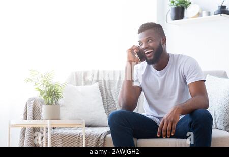 Allegro ragazzo africano che fa una data con la ragazza per telefono Foto Stock