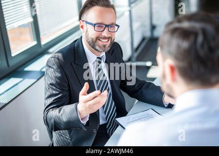 Uomini d'affari che negoziano un contratto. Mani umane che lavorano con i documenti alla scrivania e firmano il contratto. Foto Stock