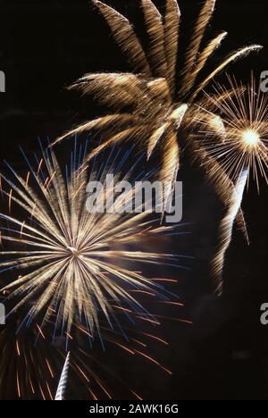 L'esplosione del display Firework crea un contrasto colorato di colori e movimenti sfocati contro un cielo notturno oscurato. Foto Stock