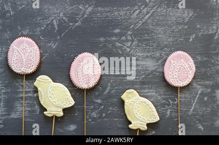 Biscotti di pan di zenzero di Pasqua decorati con vari ornamenti su uno sfondo grigio. Foto Stock