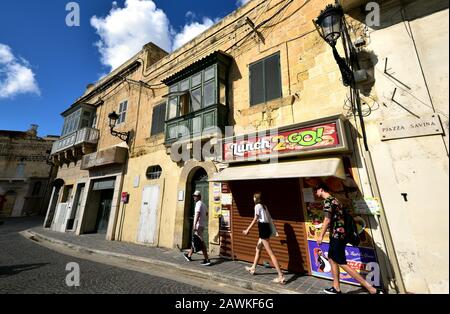 Victoria, Gozo - 8th ottobre 2018: Turisti che camminano lungo il marciapiede di Victoria Foto Stock