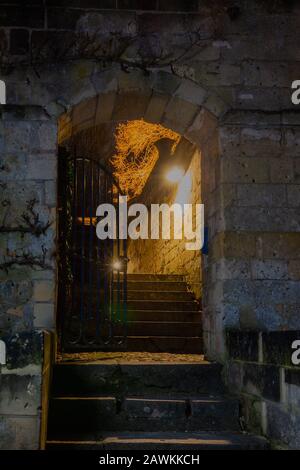 Vecchia via di passaggio con una recinzione di ferro durante la notte vicino al castello di Neercanne al confine olandese - Belgio. Questa recinzione è usata come entrata a. Foto Stock