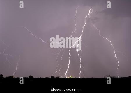 Fulmini multipli colpisce vicino e in un silo di fattoria in lontananza durante una tempesta del 2014 Arizona Monsoon. Foto Stock