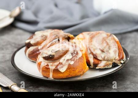 Cannella, bun danese o cinabro su sfondo scuro con tazza da caffè. Dolce pasticceria fatta in casa. Foto Stock