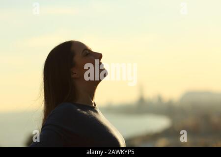 Ritratto della silhouette di una donna che respira aria fresca al tramonto Foto Stock