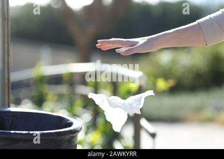 Primo piano di una donna mano gettando cucciolata fuori di un bidone in un parco Foto Stock