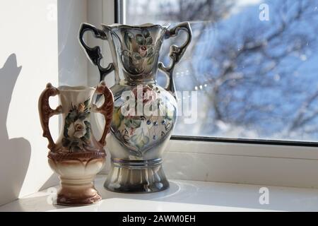 due vasi in ceramica si ergono su un davanzale con bella luce solare Foto Stock