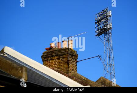 I proiettori sono visibili dietro una fila di case da terrazza Foto Stock
