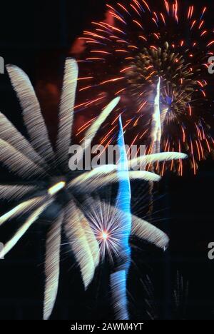 L'esplosione del display Firework crea un contrasto colorato di colori e movimenti sfocati contro un cielo notturno oscurato. Baltimora, MD, USA. Foto Stock