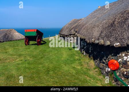 Isola di Skye: Museo con vecchie capanne e carrelli in natura vicino all'oceano con cielo drammatico. Tipico dell'Isola di Skye Foto Stock