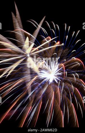 L'esplosione del display Firework crea un contrasto colorato di colori e movimenti sfocati contro un cielo notturno oscurato. Baltimora, MD, USA. Foto Stock