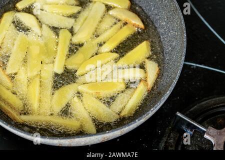 Patatine fritte che friggono in olio vegetale nella padella sul fornello Foto Stock