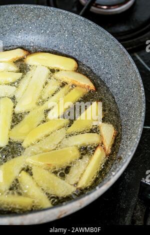 Patatine fritte che friggono in olio vegetale nella padella sul fornello Foto Stock