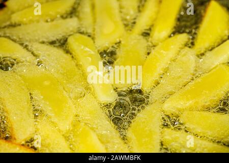 Patatine fritte che friggono in olio vegetale nella padella sul fornello Foto Stock