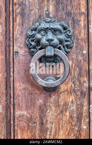 dettaglio di un antico leone testa ferro bussare su una porta di legno Foto Stock