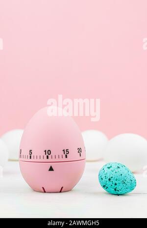 Cucina rosa uovo timer su sfondo rosa. Tempo di cottura, presto Pasqua. Uova di gallina bianca e uova di quaglia blu. Copia spazio Foto Stock
