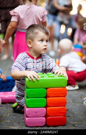 Carino ragazzo giocando con il giocattolo edili blocchi colorati. Il capretto con faccia felice giocando con mattoni di plastica. Plastica giocattolo di grandi dimensioni. Foto Stock