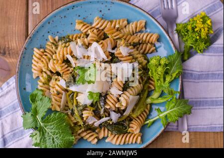 Cime di rapa in un piatto con parmigiano su un tavolo di legno. Cucina tradizionale del sud d'Italia, dalla Puglia. Foto in stile rustico. Foto Stock