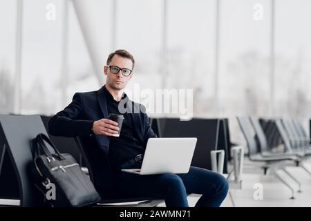 Giovane uomo d'affari seduto sul computer all'aeroporto in attesa del volo. Foto Stock
