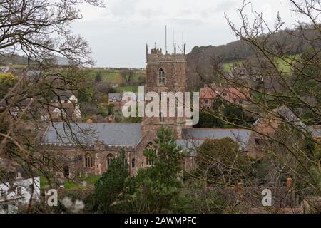 Vista in lontananza della Chiesa di Santa Maria nel Dunster Somerset. Parzialmente oscurato da alberi in primo piano. Foto Stock