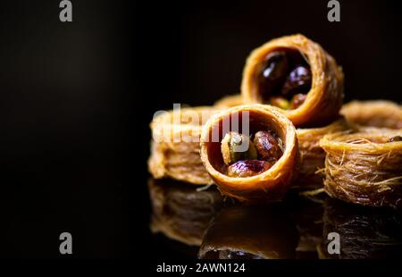 Dessert arabo con pistacchio riflesso su sfondo scuro Foto Stock