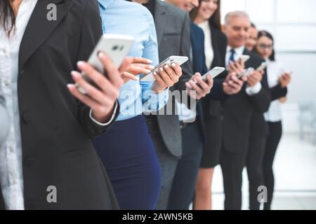 gruppo di dipendenti diversificati con smartphone in fila Foto Stock