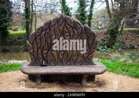 Un sedile a panchetta in legno con un alto schienale finemente scolpito che presenta diversi animali selvatici nel parco giochi Welshmill Frome Somerset Foto Stock