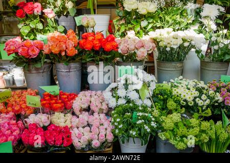 Vista frontale di vari bouquet di rose e fiori in vasi di metallo sul ripiano di fronte alla stalla di fiori o negozio floreale al mercato agricolo in Europa. Foto Stock