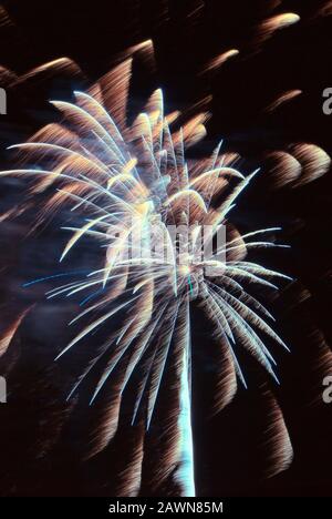 L'esplosione di fuochi d'artificio crea un contrasto colorato di colore e di movimento sfocato contro un cielo notturno oscurato a Baltimora MD USA. Foto Stock