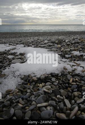 Colpo verticale di neve scongelamento sui ciottoli sul spiaggia Foto Stock