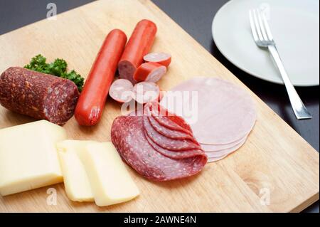 Vista ad alto angolo di una tradizionale colazione tedesca su una tavola di legno con affettati a fette, tra cui salumi speziati e salsicce serviti con formaggio per A. Foto Stock