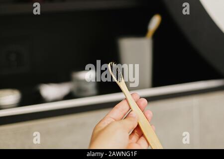 Spazzolino da denti in bambù naturale in bagno moderno sullo sfondo di elegante ripiano nero con elementi biologici naturali in plastica. Zero wast Foto Stock