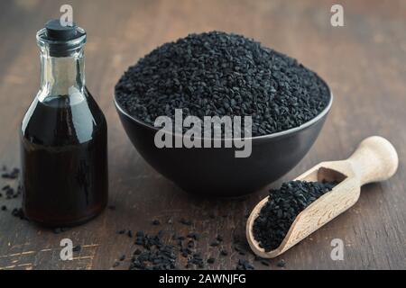 Semi di cumino nero o coriandolo romano e bottiglia di olio di cumino nero. Ingredienti per cucinare. Trattamenti ayurvedici naturali. Foto Stock