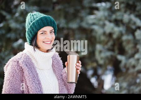 Giovane donna che cammina il giorno dell'inverno, viaggia in acciaio inox con caffè caldo. Bottiglia d'acqua riutilizzabile. Rifiutare, ridurre, riciclare e azzerare i rifiuti c Foto Stock