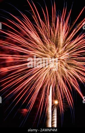 L'esplosione di fuochi d'artificio crea un contrasto colorato di colore e di movimento sfocato contro un cielo notturno oscurato a Baltimora MD USA. Foto Stock