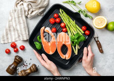 Bistecche di salmone crudo e verdure su una padella grigliata in ghisa pronta per la cottura. Cibo sano, concetto di cibo pulito Foto Stock