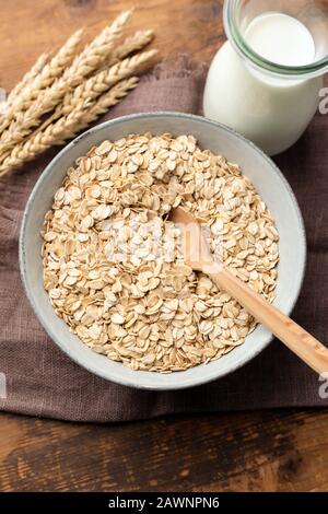 Fiocchi di avena, fiocchi di avena laminati in ciotola su un fondo di tabella di legno. Sano mangiare, dieta concetto Foto Stock