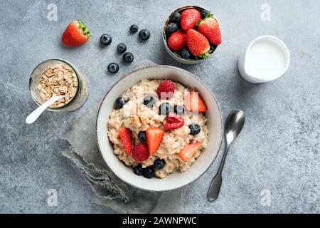 Ciotola di sana colazione farina d'avena porridge ciotola servita con bacche estive. Vista dall'alto del tavolo. Cibo pulito, dieta, cibo vegetariano Foto Stock