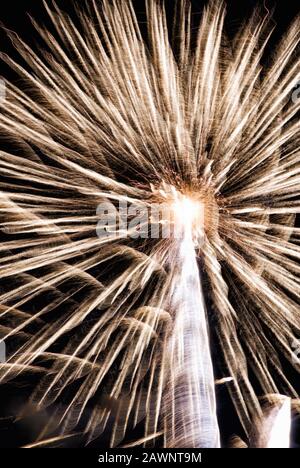 L'esplosione del display Firework crea un contrasto colorato di colori e movimenti sfocati contro un cielo notturno oscurato. Foto Stock