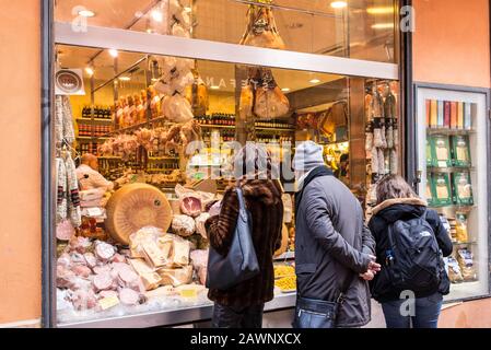 Bologna, Italia - Dicembre 2019: Persone che guardano vetrine con piatti tipici italiani in Via Pescherie vecchie, un famoso vicolo pieno di tradizionali Foto Stock