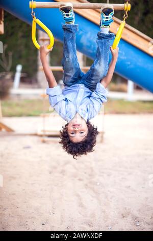 Un ragazzo sorridente che si arrampica al parco giochi all'aperto. Concetto di infanzia e attività Foto Stock