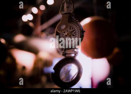 Bellissimo bokeh di fondo di una bussola appeso con luci e riflessioni in background. Concetto di essere perduti, libertà e ricerca della felicità. Foto Stock