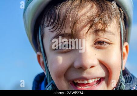 Ritratto di un giovane ragazzo all'aperto che indossa un casco da bicicletta e sorridente. Foto Stock