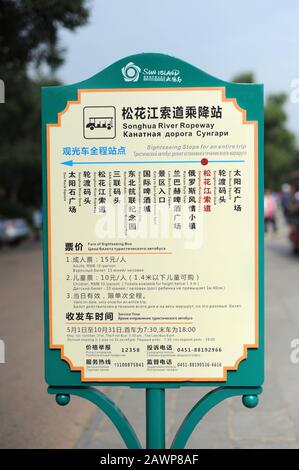 Cartello multilingue per il minibus turistico alla fermata della stazione cablepar nel parco sul lato opposto del fiume Songjiang, Harbin, Cina Foto Stock