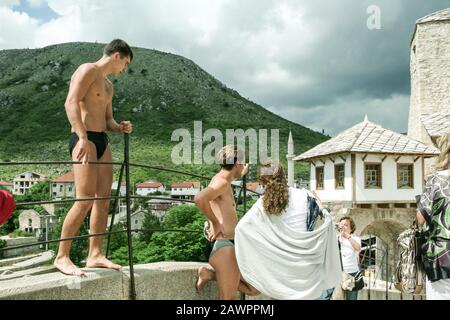 Mostar, BOSNIA-ERZEGOVINA - 6 GIUGNO 2008: Donne anziane, turisti, scattare foto di uomini in costume da bagno pronto a saltare dal Ponte Vecchio di Mostar in t. Foto Stock