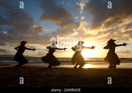 Quattro ballerini di hula al tramonto a Palauea, Maui, Hawaii. Foto Stock