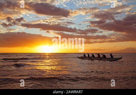 Outrigger canoa padders a Cove Park, Kihei, Hawaii al tramonto. Foto Stock