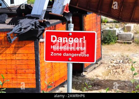 Un cartello rosso di pericolo per le aree pericolose in inglese e francese Foto Stock