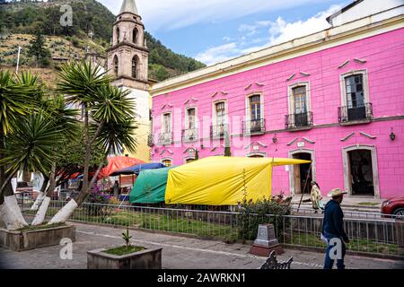 Il Parroquia de San Simón Apostol e il rosa Hotel Jardin sulla Plaza de la Constitucion di Angangueo, Michoacan, Messico. Angangugueo è una piccola e remota cittadina di montagna e il punto di ingresso al Santuario delle farfalle di Sierra Chinccua Monarch. Foto Stock