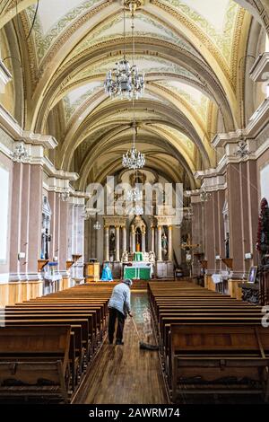 Una donna spazza il pavimento nella vecchia chiesa Parroquia de San Simón Apostol di Angangueo, Michoacan, Messico. Angangugueo è una piccola e remota cittadina di montagna e il punto di ingresso al Santuario delle farfalle di Sierra Chinccua Monarch. Foto Stock